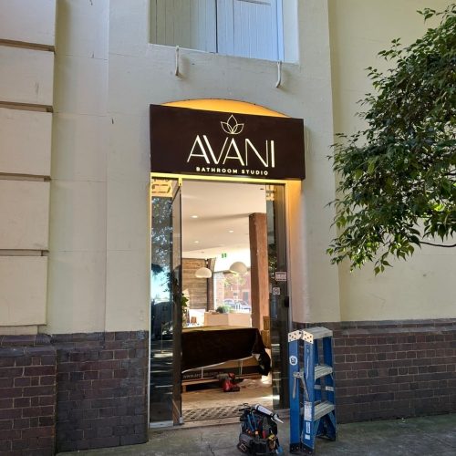 A retail sign above a doorway with lighting behind it.
